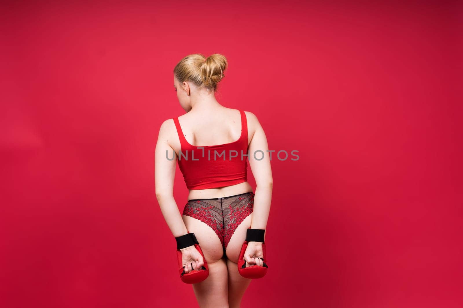 Image of seductive young woman boxer posing isolated on yellow red background in boxing gloves.