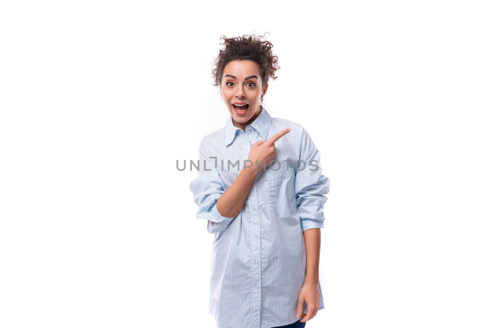 young surprised curly brunette secretary woman dressed in a light blue shirt on a white background with copy space.