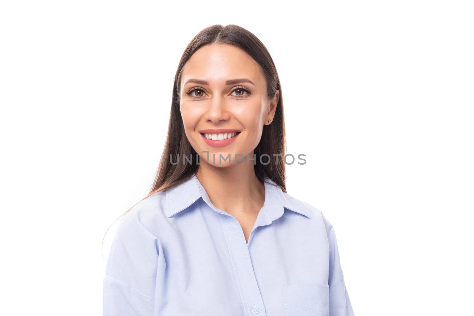 portrait of a young caucasian model woman with light makeup and dark straight hair dressed in a blue blouse on a white background with copy space.