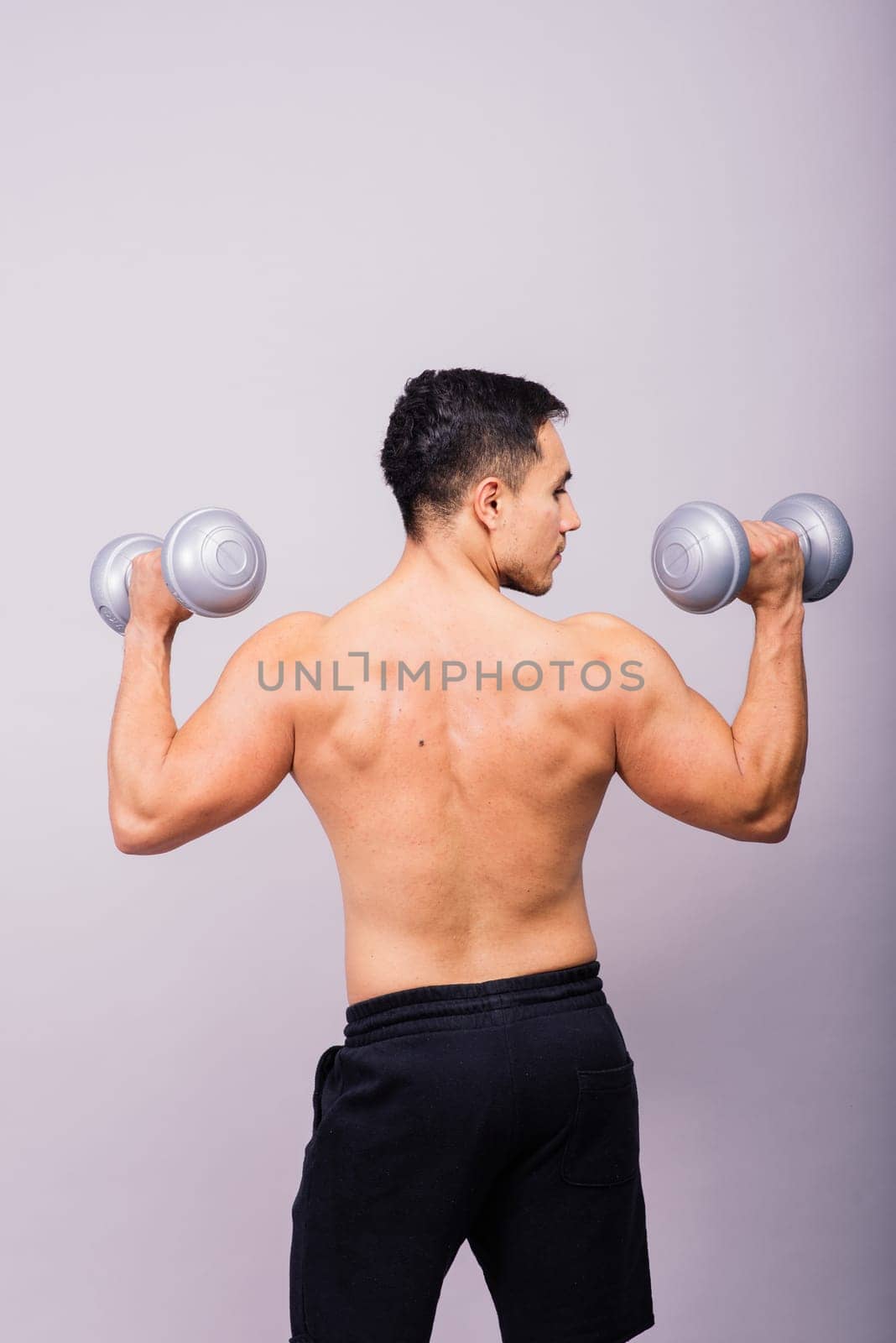 Shirtless bodybuilder showing his great body and holding dumbells.