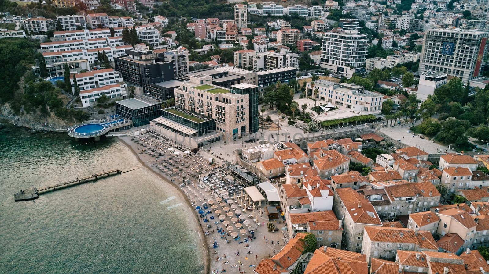 Beach with sun umbrellas on the seashore between the old and new parts of Budva. Montenegro. Drone. High quality photo