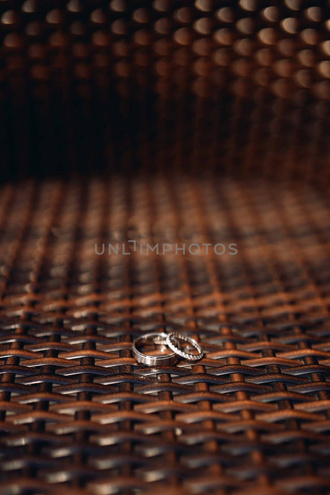 Wedding rings lie on a brown wicker chair. High quality photo