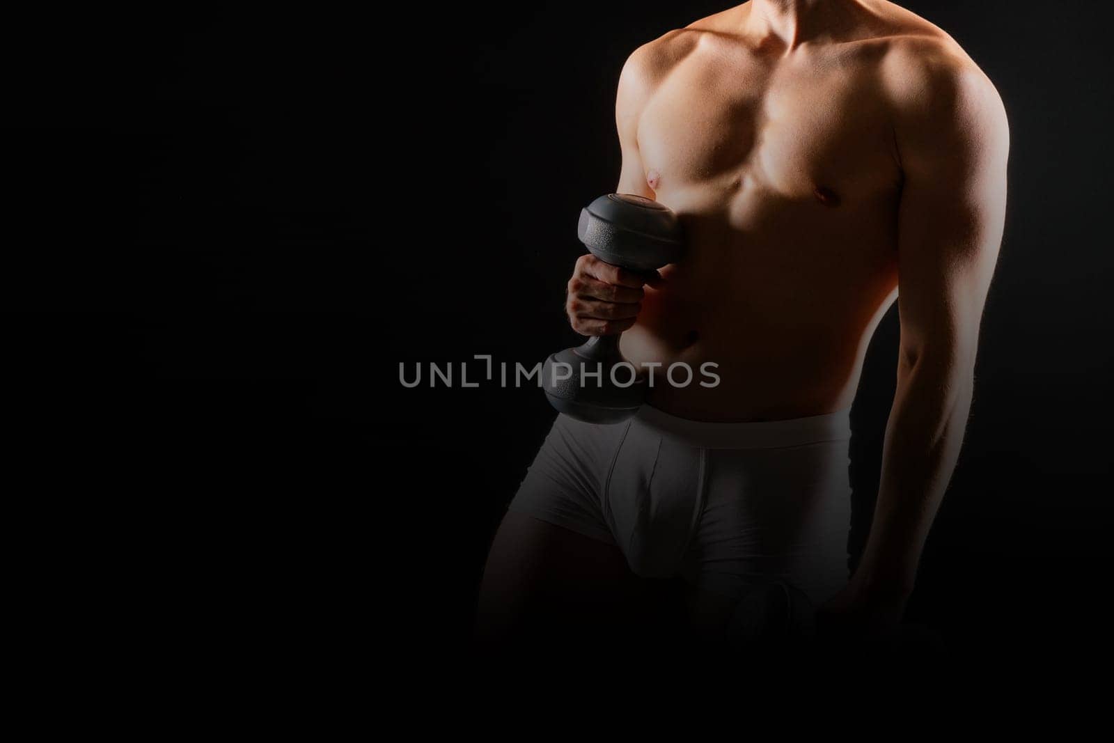 Man with pumped-up body with dumbbells in his hands white panties exercise