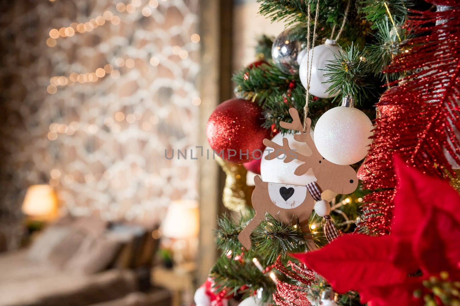 Magic glowing tree. Christmas home interior with Christmas tree. Red and white balls hanging on pine branches. Festive lights in the brick wall background.