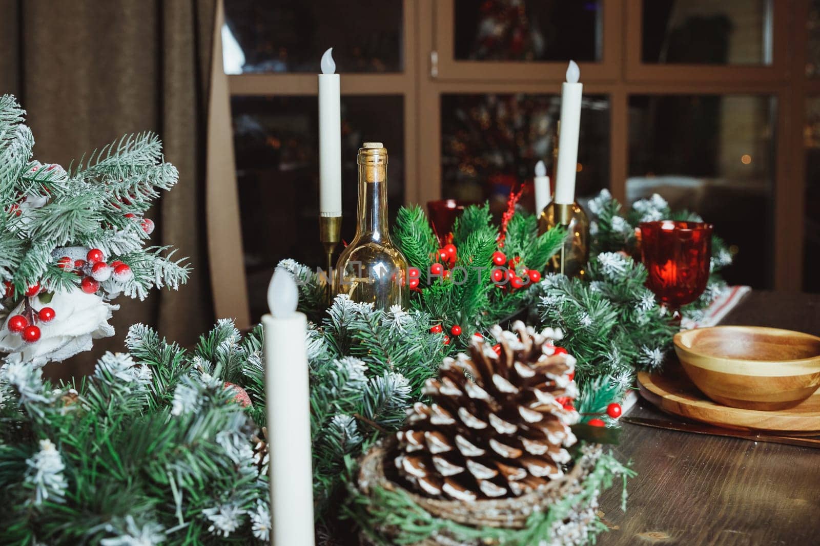 Festive table setting among winter decorations and white candles. Top view, flat lay. The concept of a Christmas or Thanksgiving family dinner.
