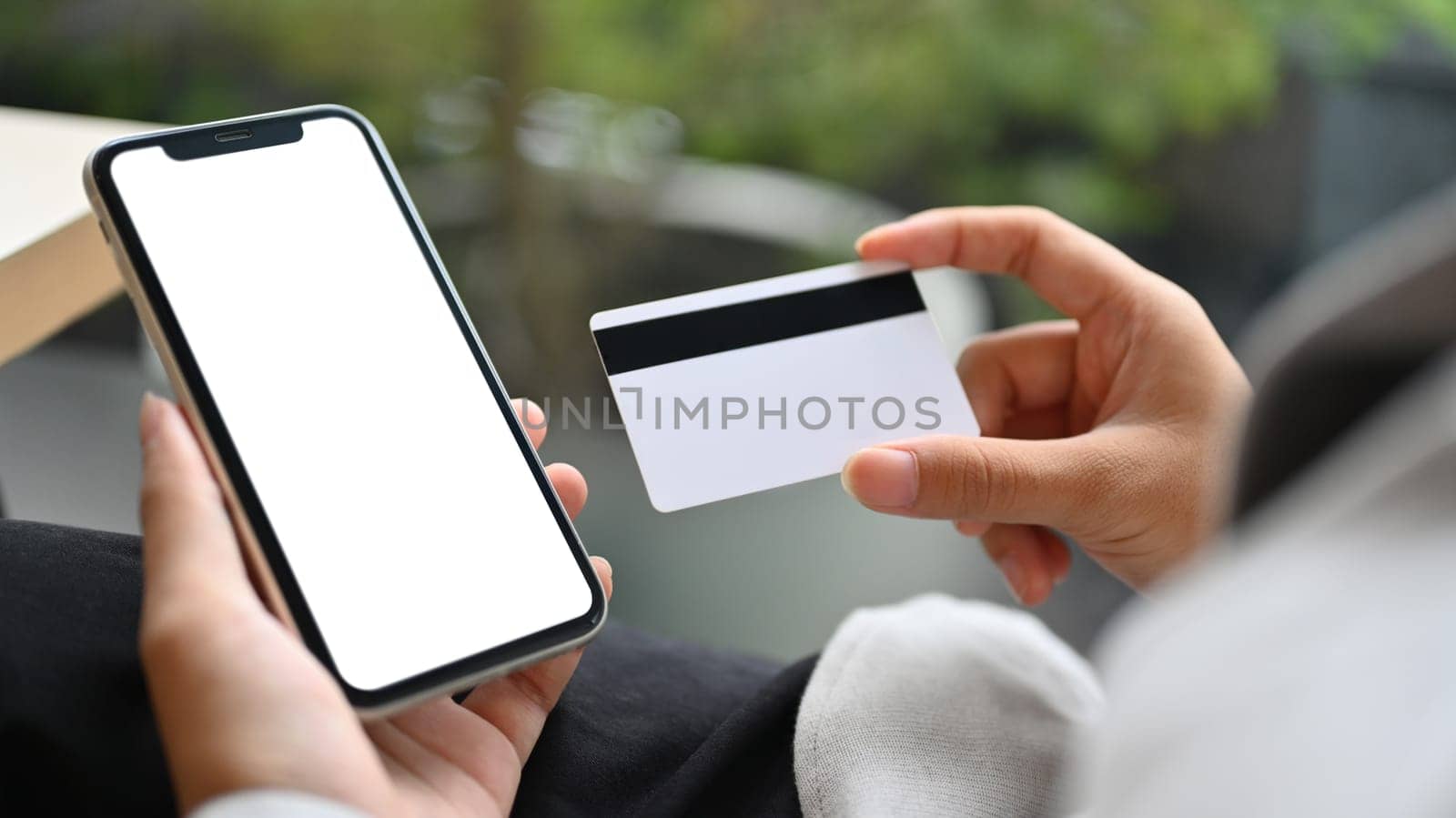 Woman holding credit card and using mobile phone making payment or ordering via the internet.