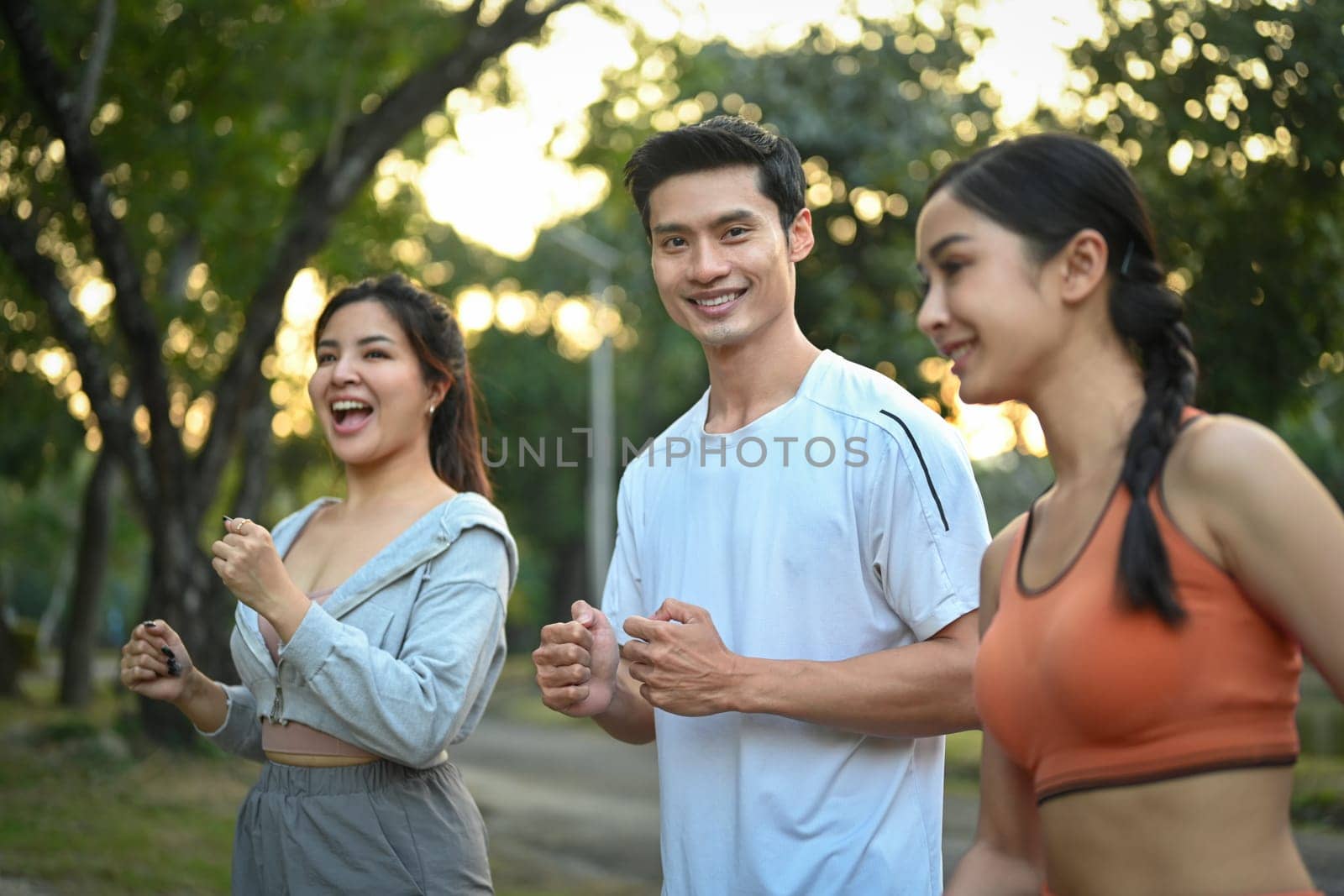 Group of sporty young people jogging together in the morning sunrise. Healthy Lifestyle concept.