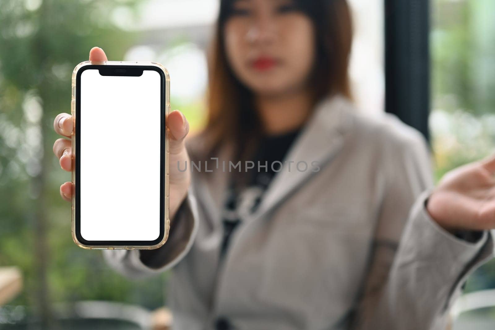 Young woman showing mobile phone with empty white screen for recommending mobile application.