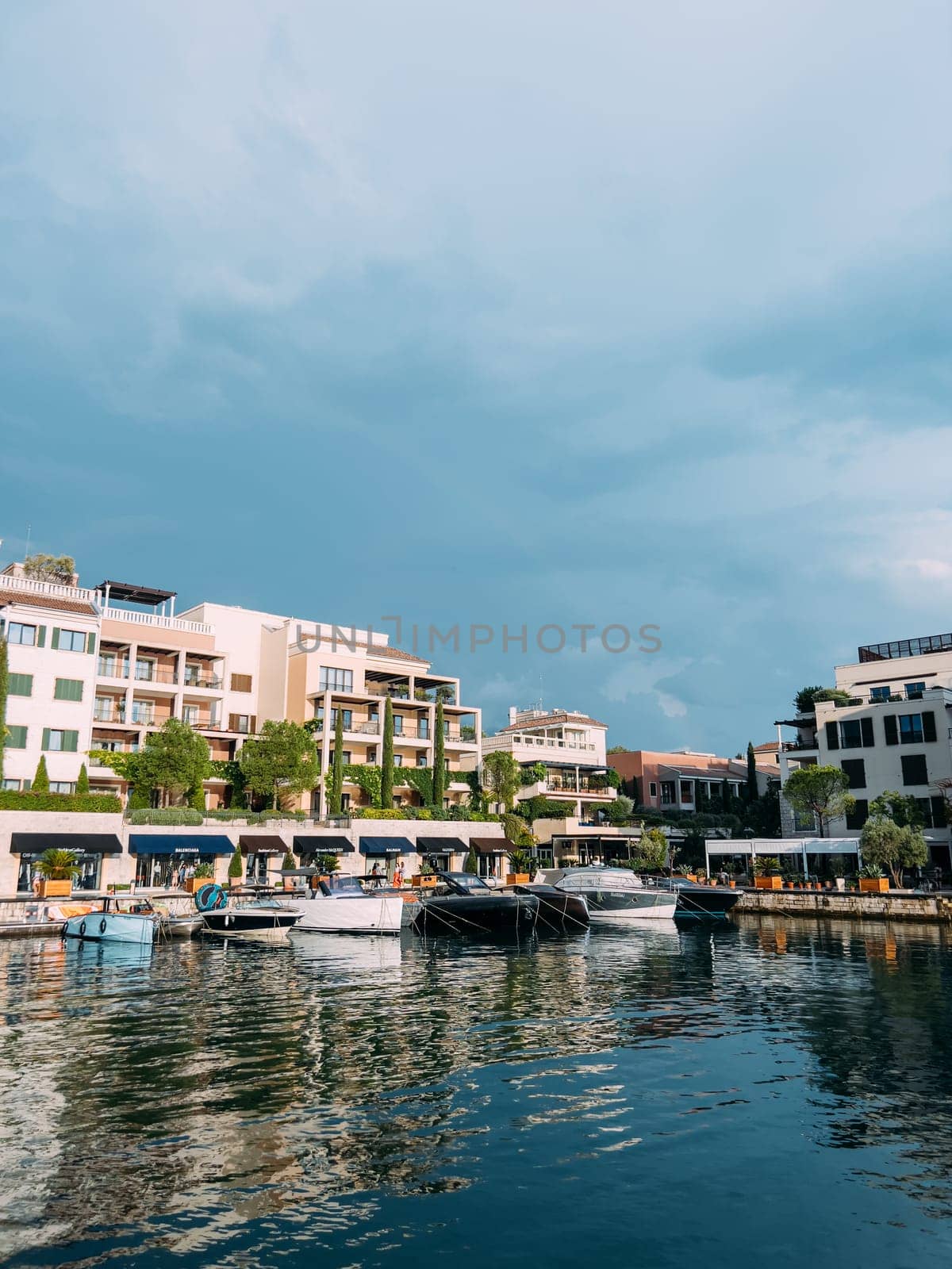 Motor yachts are moored along the shore with colorful hotels and expensive shops. Porto, Montenegro. High quality photo
