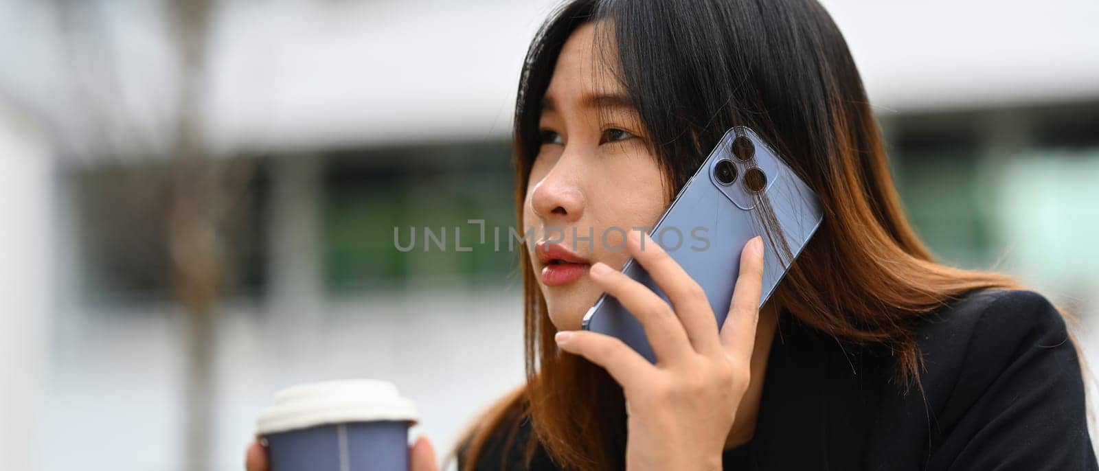 Horizontal image of young businesswoman talking on mobile phone and looking away.