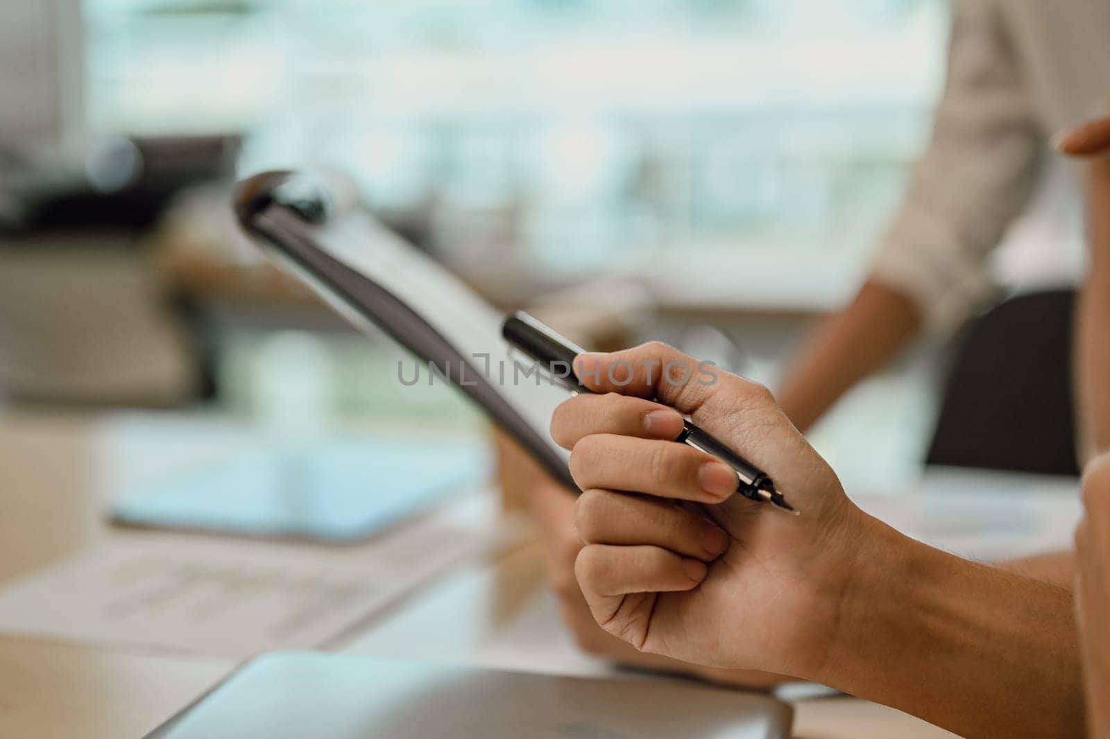 Cropped shot of unrecognizable businessman sitting at meeting table and holding pen.