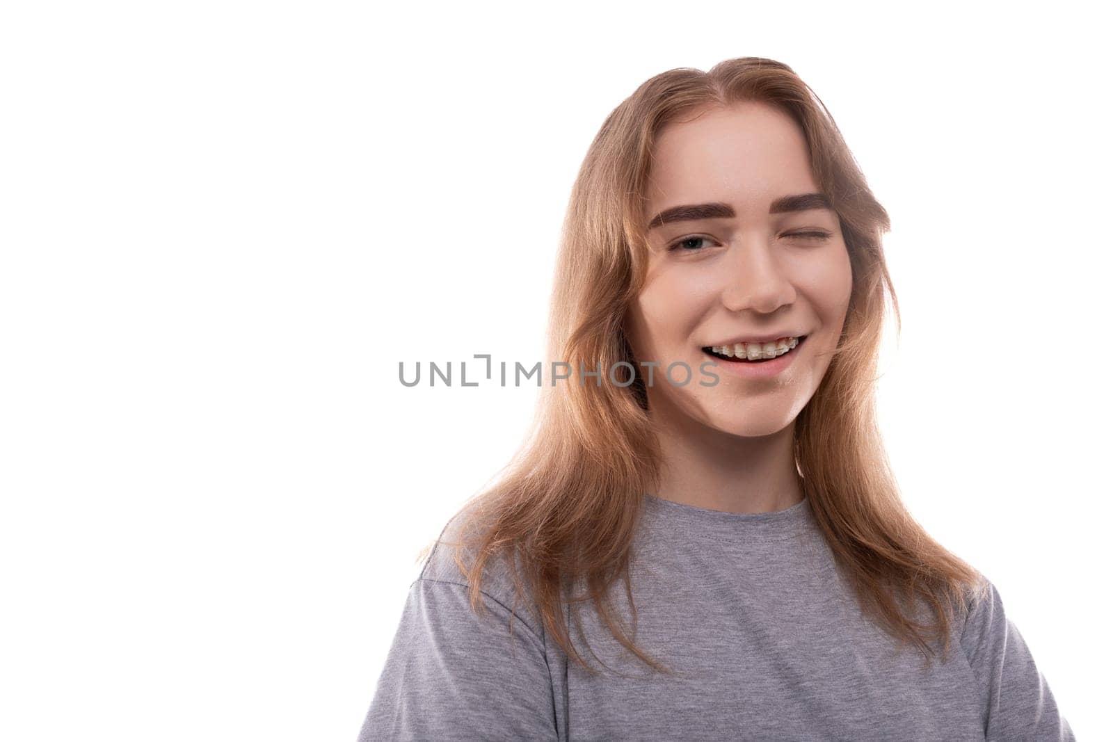 Headshot portrait of laughing teenage girl in gray t-shirt.
