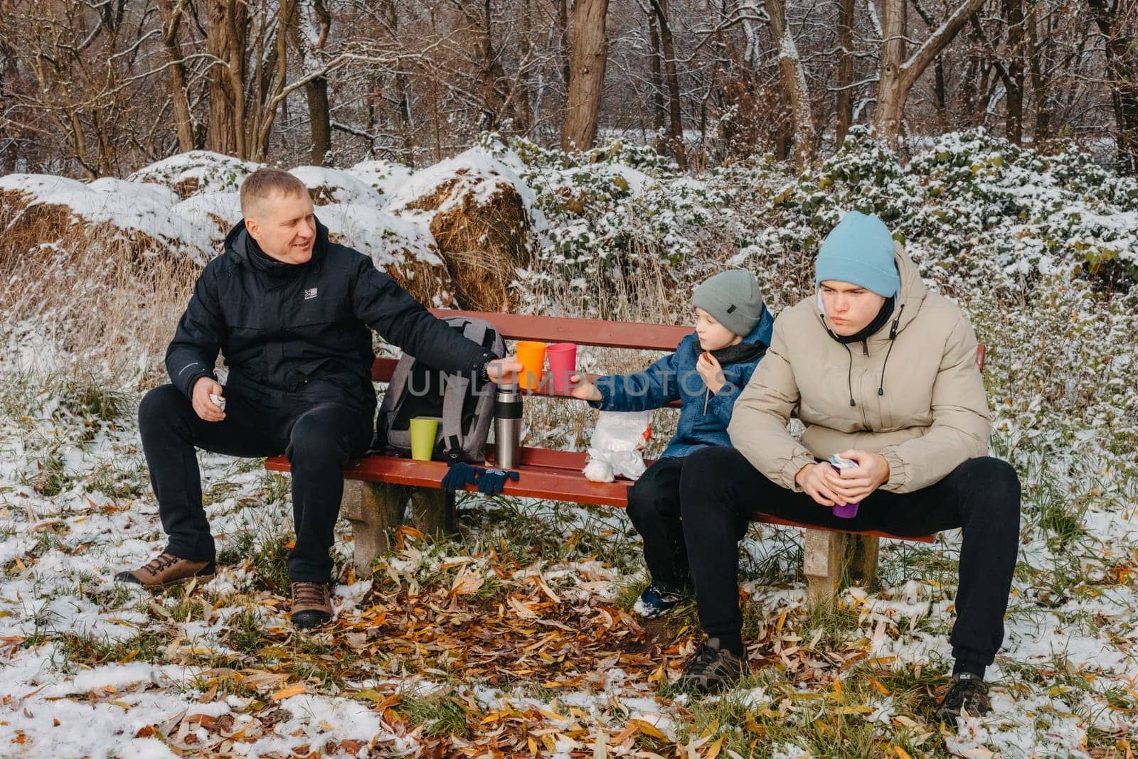 Snowy Park Serenity: Dad and Sons Share Treats and Smiles in a Winter Wonderland. Winter's Togetherness: A Delightful Bench Picnic with Dad and the Boys. A Heartwarming Winter Picnic with Father and Sons in a Snow-Kissed Park by Andrii_Ko