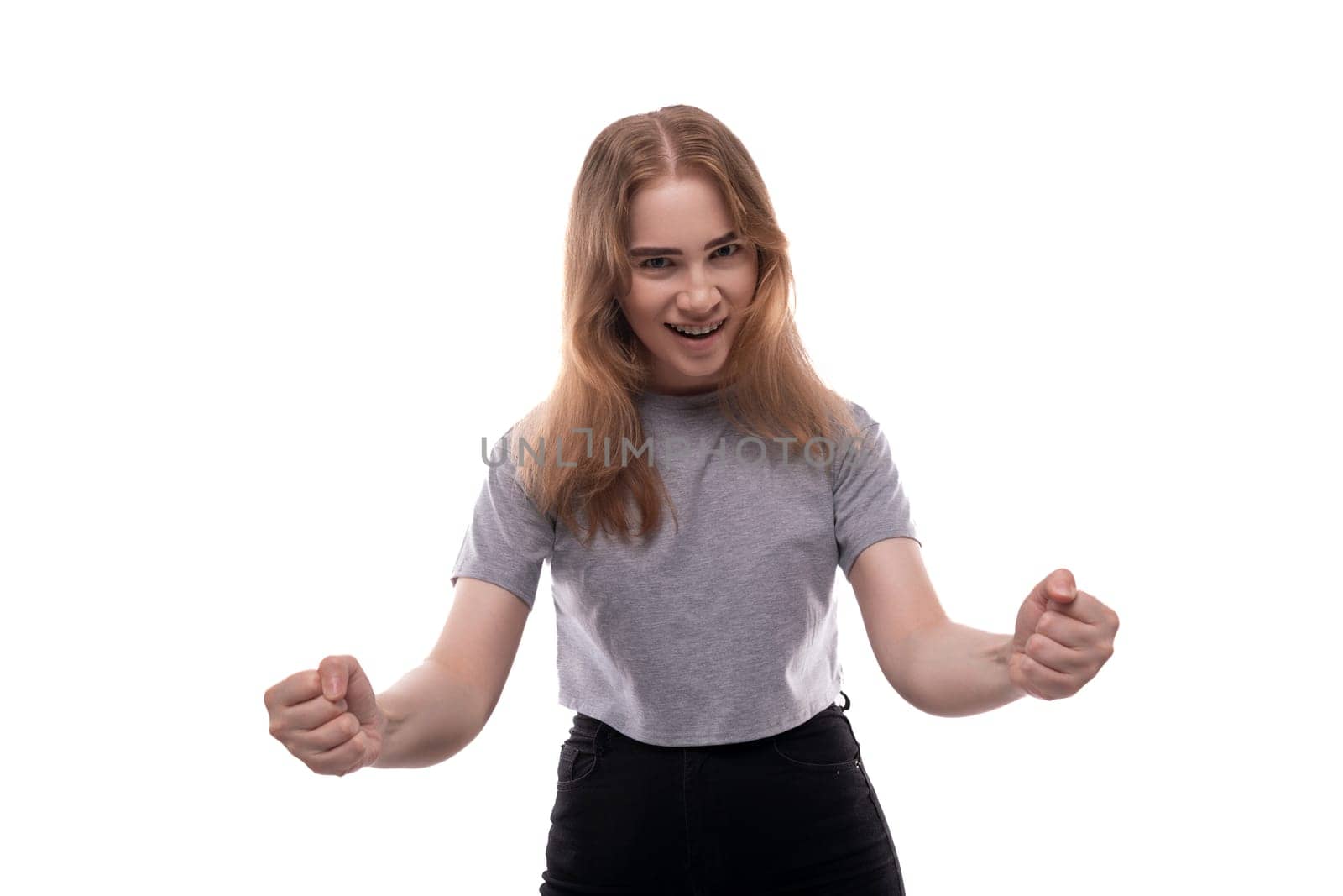 Portrait of a teenage girl with blond hair in a gray T-shirt on a white background by TRMK