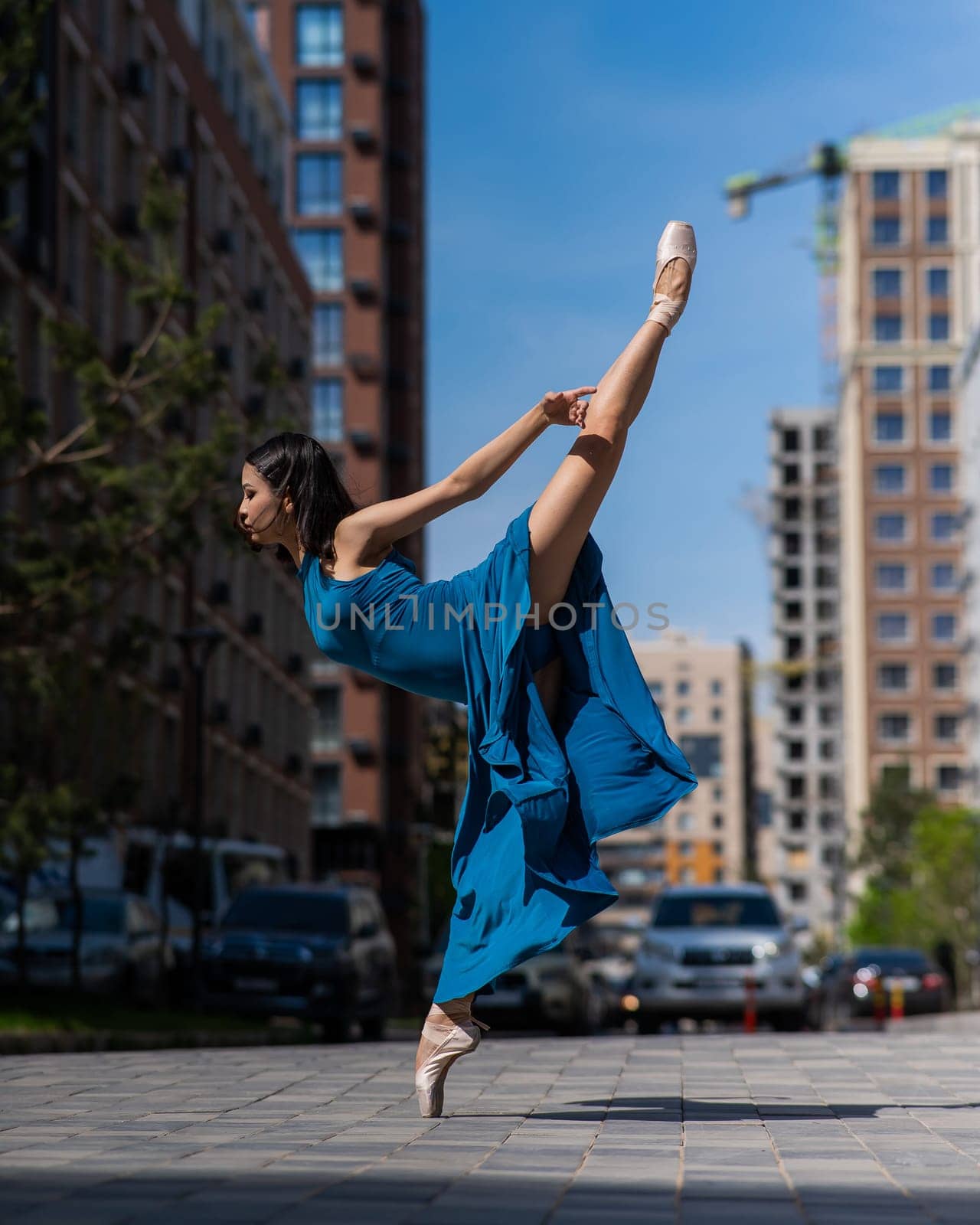 Beautiful Asian ballerina dancing outdoors. Urban landscape