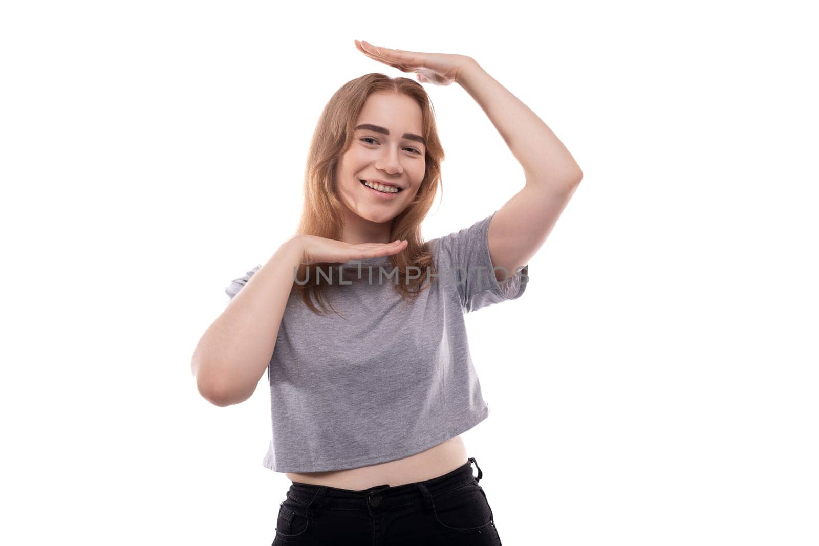Blonde teenage girl of European appearance with braces in a gray T-shirt on a background with copy space.