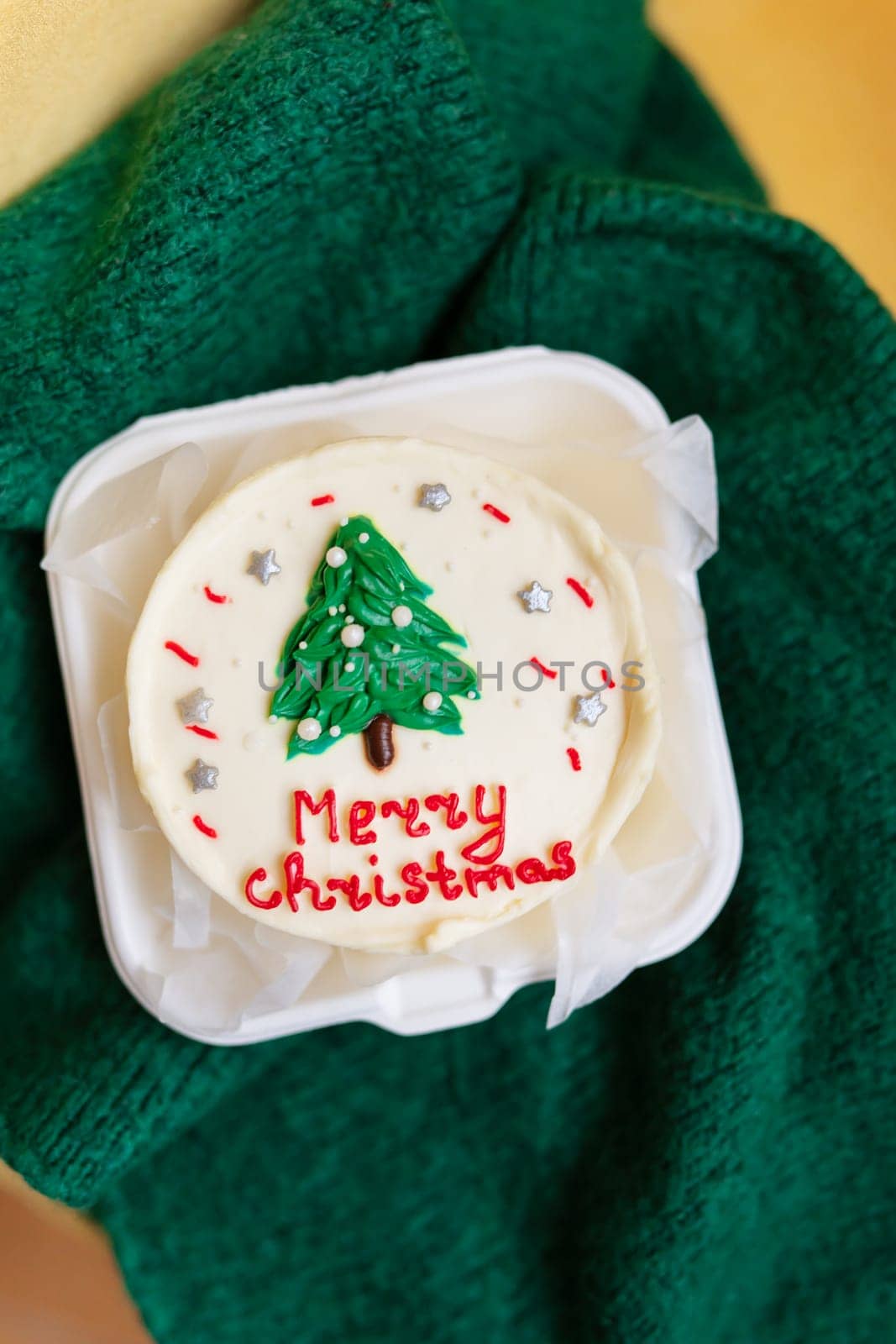 A festive Christmas cupcake with a green tree and red Merry Christmas text on a white frosting
