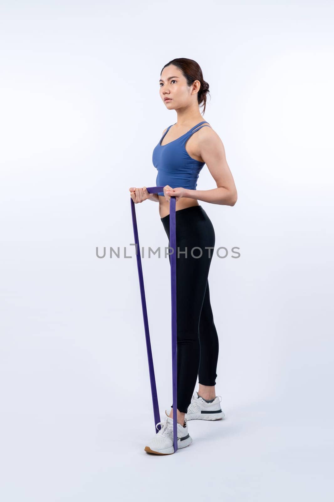 Vigorous energetic woman in sportswear portrait stretching resistance band. by biancoblue