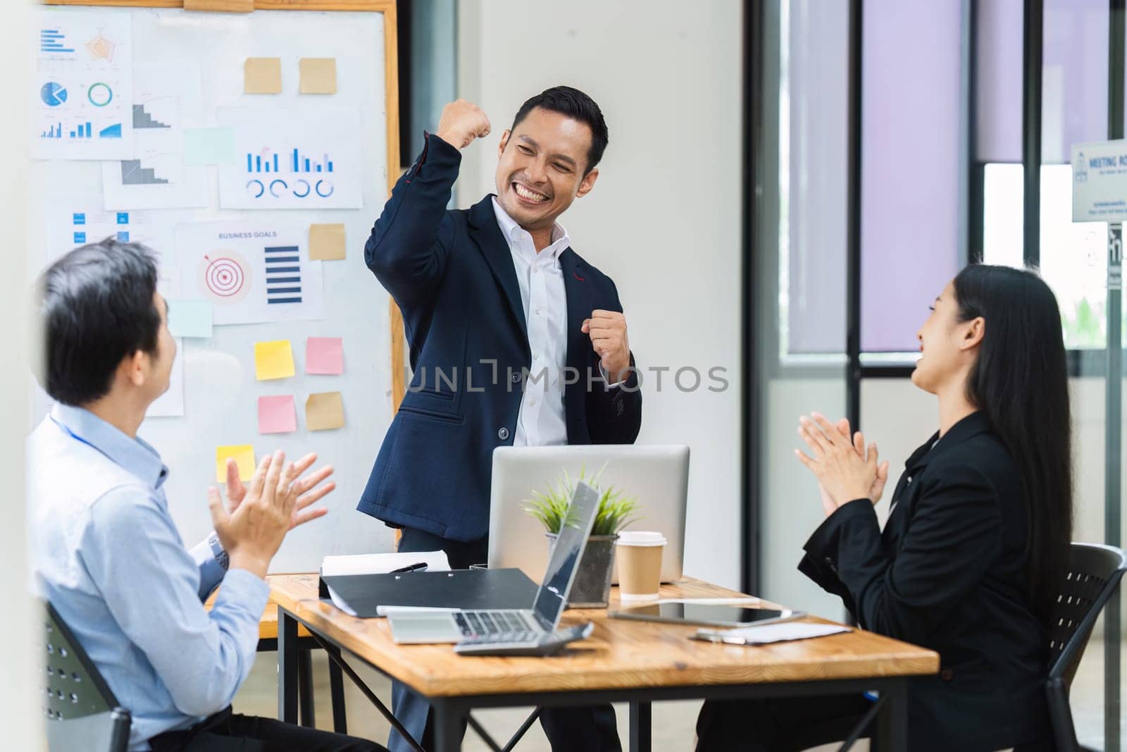 Man professional celebrate with colleague in conference room. Group of colleagues celebrating success in a meeting.