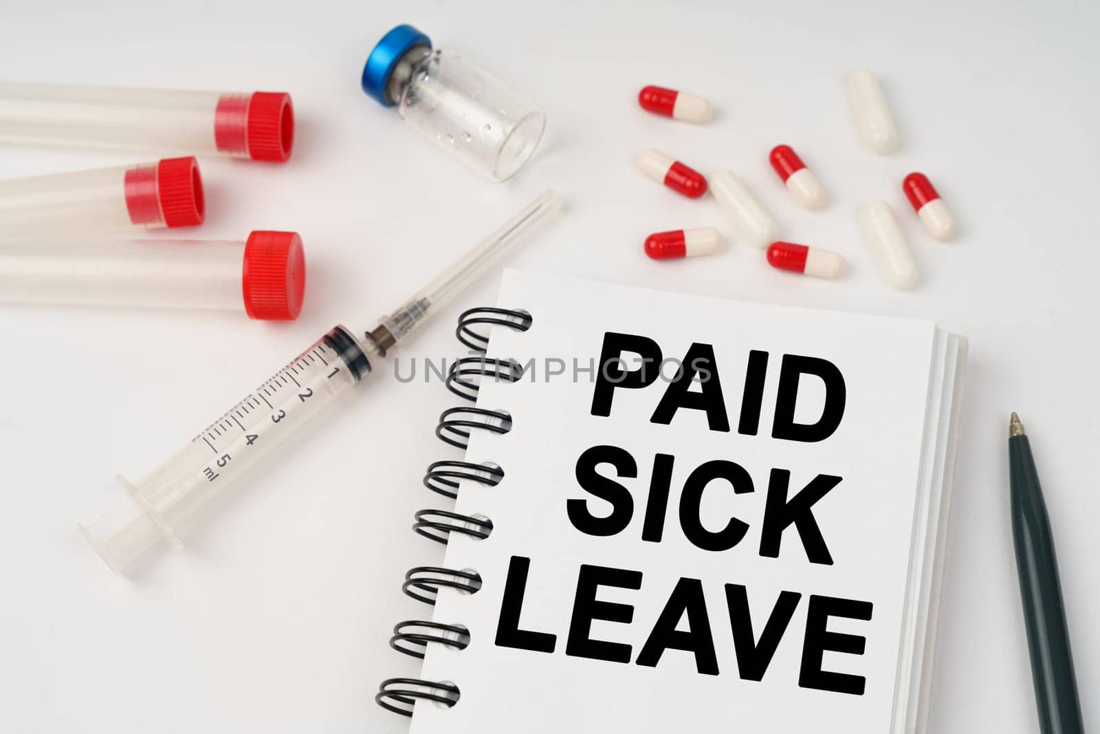 Medical concept. On the table are pills, injections, a syringe and a notepad with the inscription - Paid sick leave