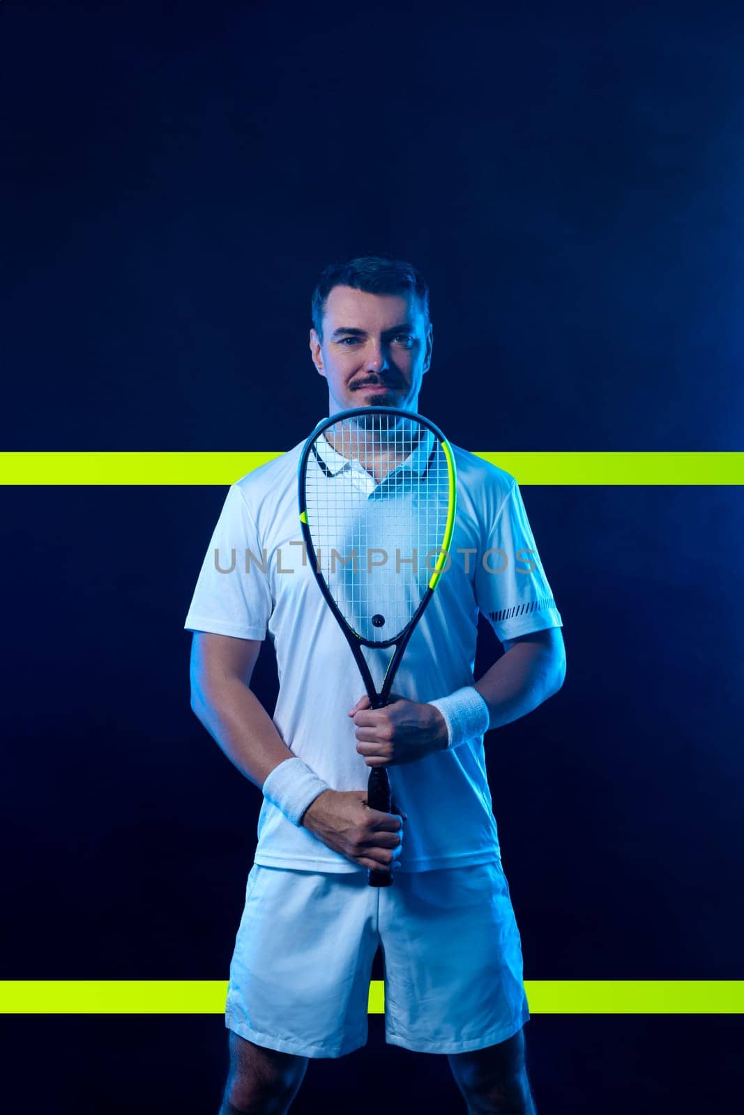 Squash player on a squash court with racket. Man athlete with racket on court with neon colors. Sport concept. Download a high quality photo for the design of a sports app or betting site. by MikeOrlov