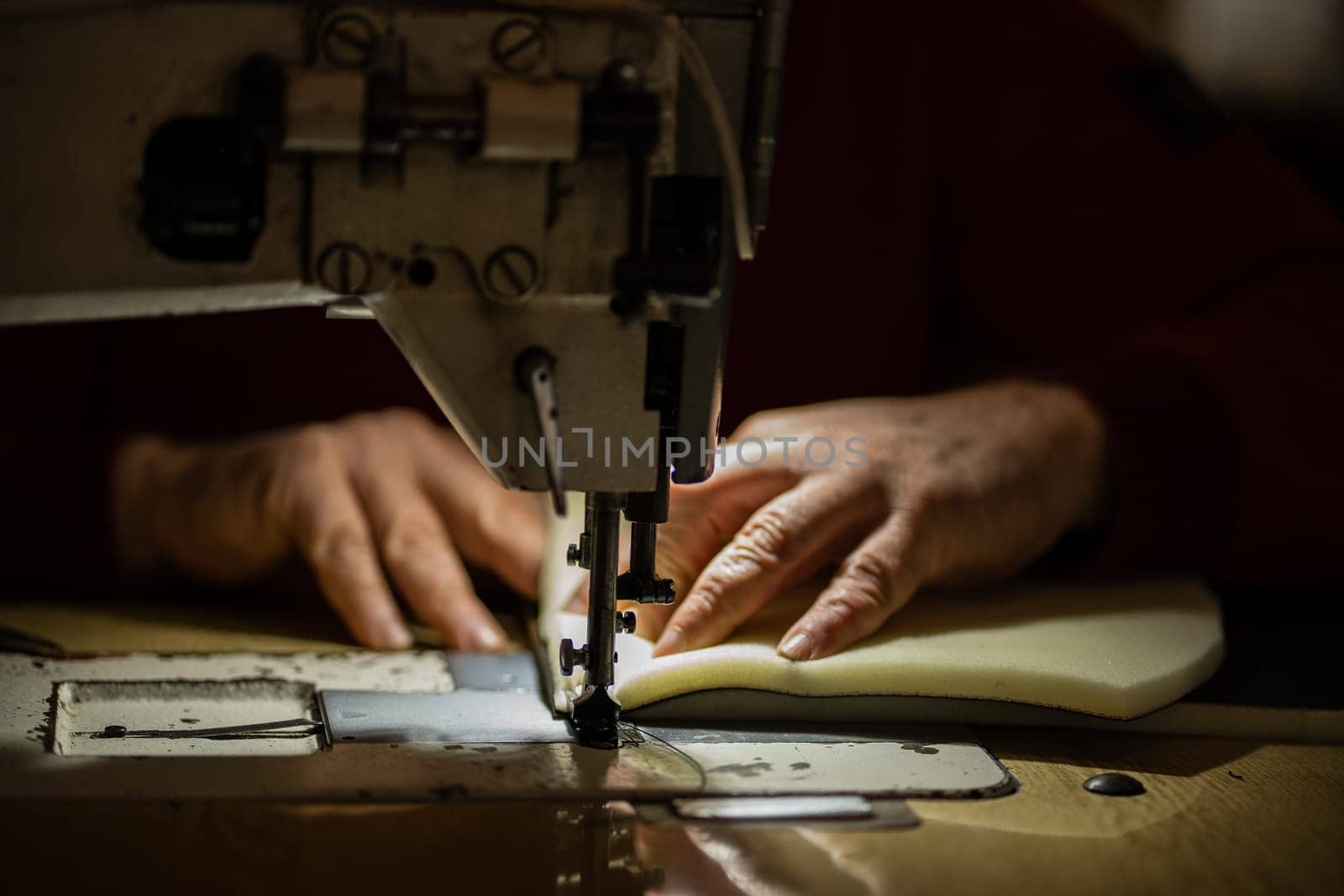 Sewing machine and men's hands of a tailor needle in focus