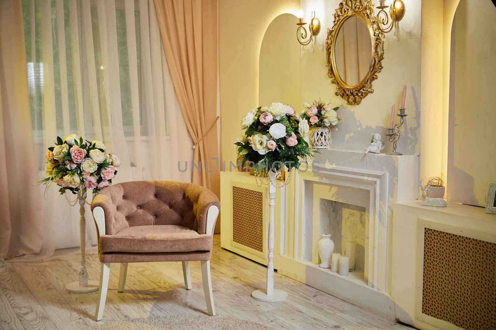 Interior of stylish living room with fireplace. A beautiful room with armchair, a fireplace, a mirror and bouquets of flowers. A photo studio, a place for photo shoots, a location for shooting