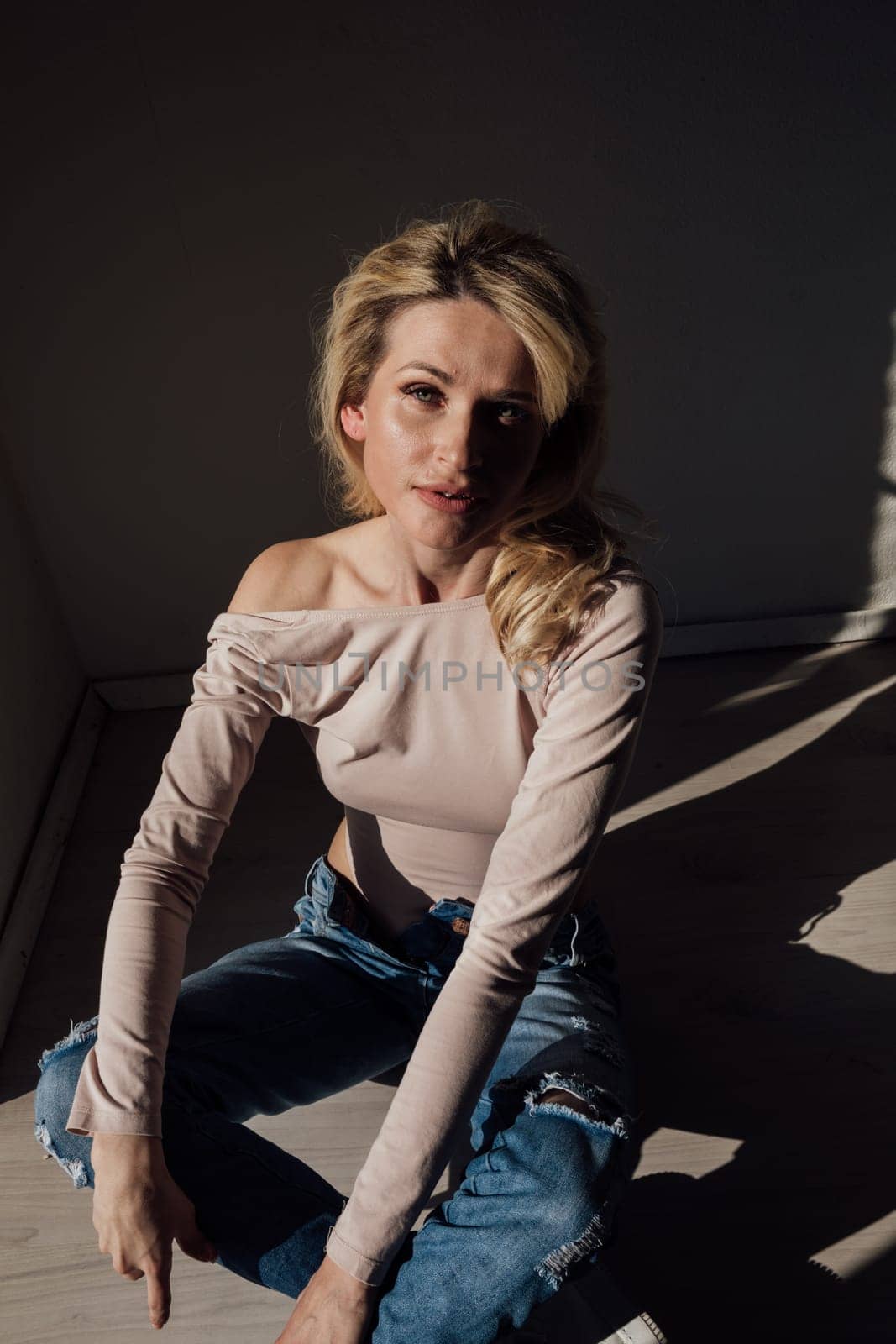 Beautiful fashionable blonde woman light and shadow from blinds