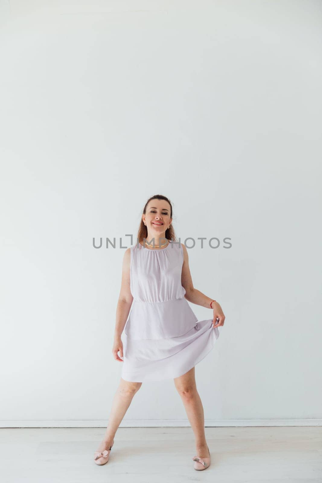 Beautiful brunette woman in light light dress on white background