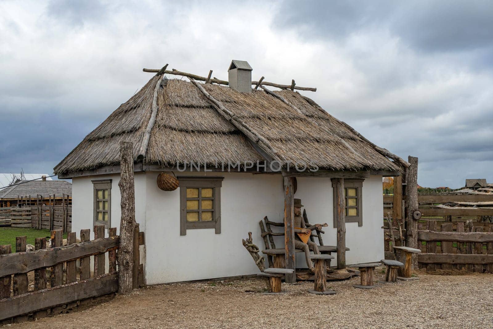 An old white house in the Ukrainian vintage style. house with a cattail roof. Roof is made of reeds