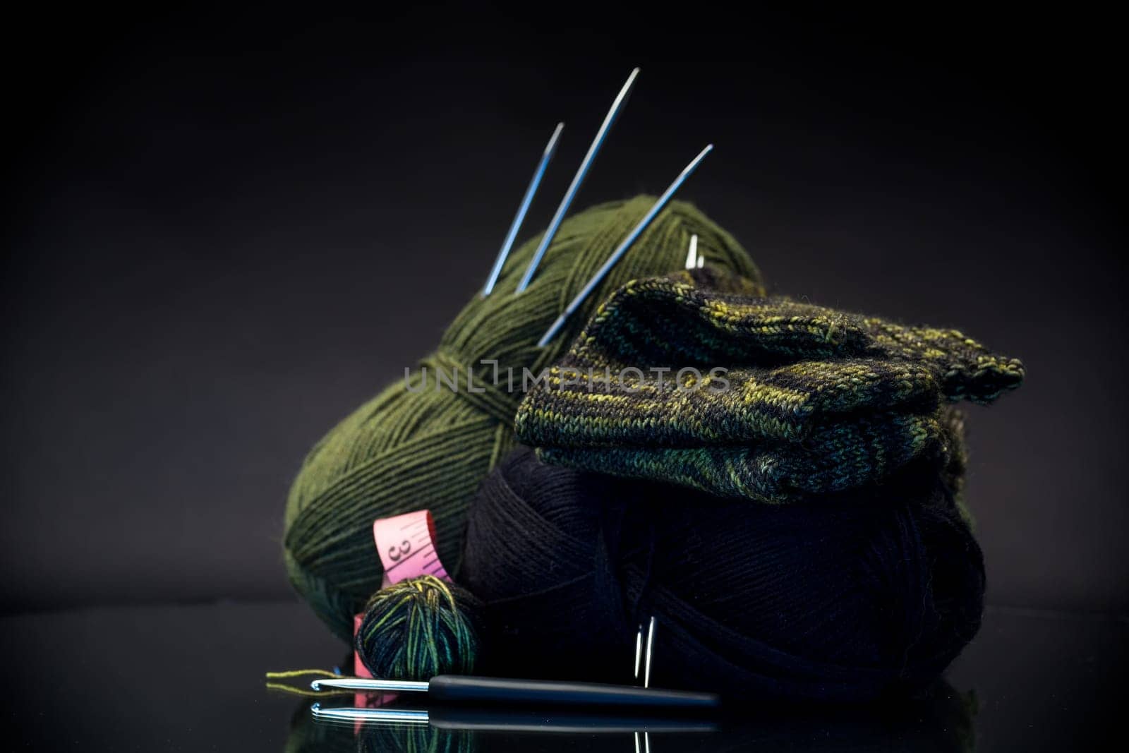 wool yarn, knitting needles and other tools for hand knitting, isolated on a black background.