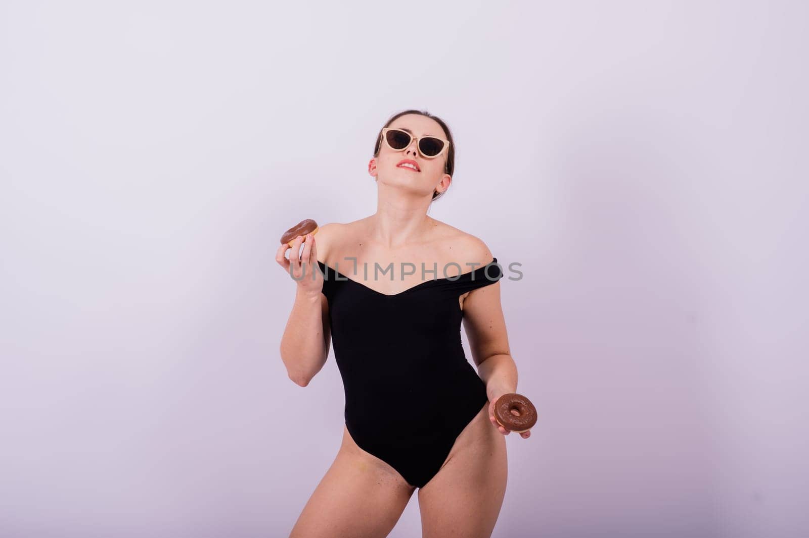Close up shot of nude woman's body with chocolate covered donuts