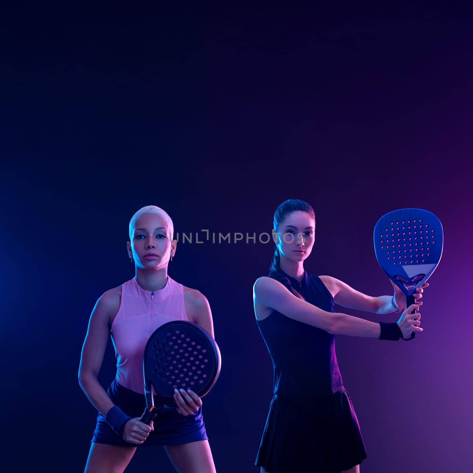 Two padel tennis players with racket. Girl teenager athlete with racket on court with neon colors. Sport concept. Download a high quality photo for the design of a sports app or betting site