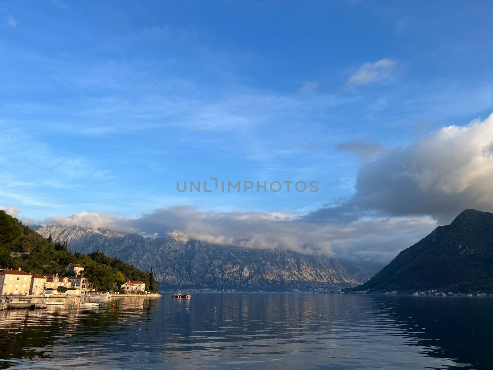 Perast embankment with moored fishing boats at the foot of the mountains. Montenegro. High quality photo