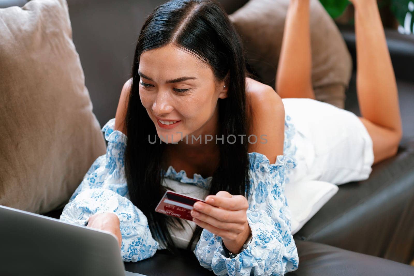 Young woman using laptop with credit card for internet banking, online shopping E commerce by online payment gateway at home office. Modern and convenience online purchasing with debit card. Blithe