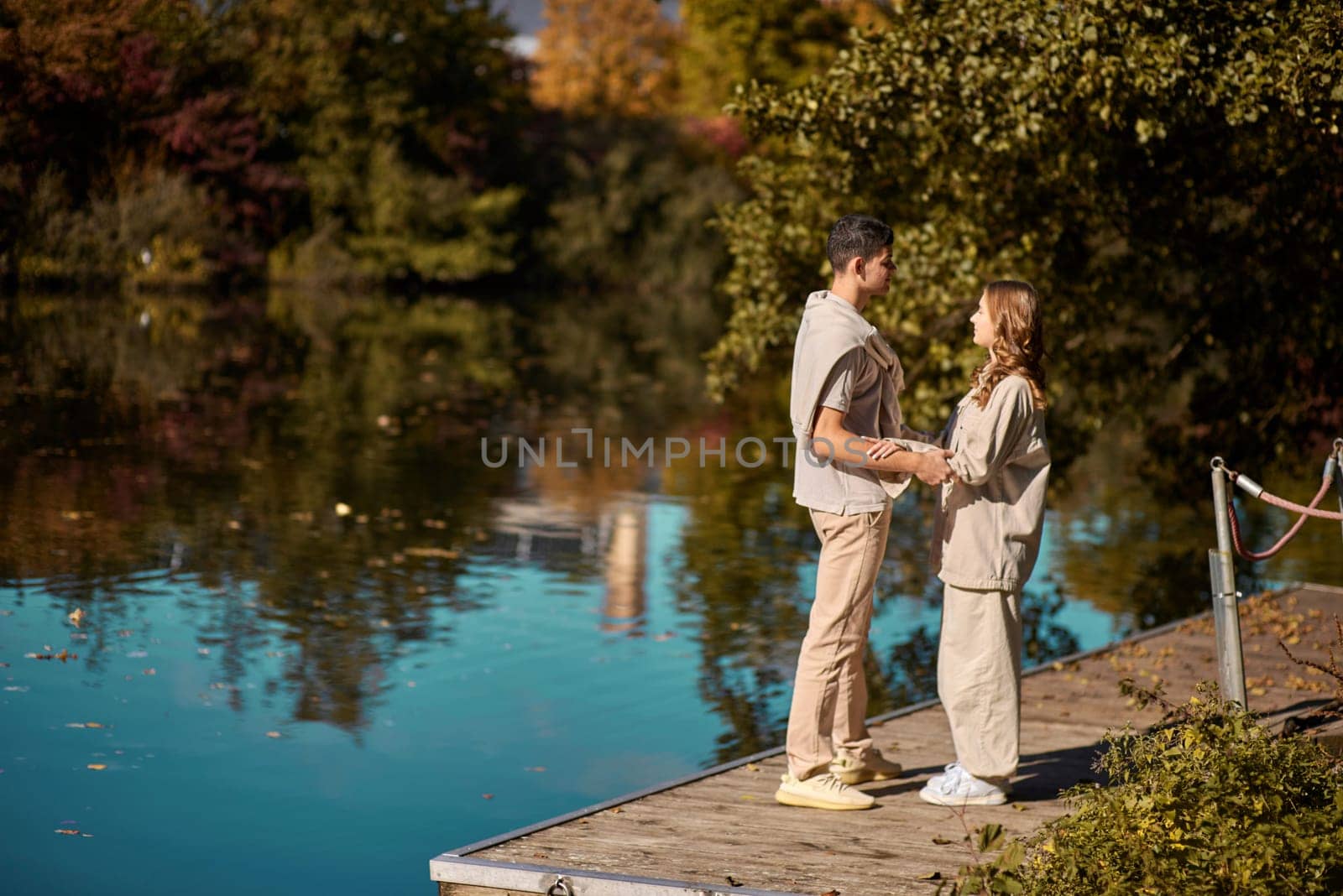 A guy carrying a girl on his back, at the beach, outdoors. River. Young Girl And Guy Love. Handsome young man kissing his girlfriend near the river by Andrii_Ko