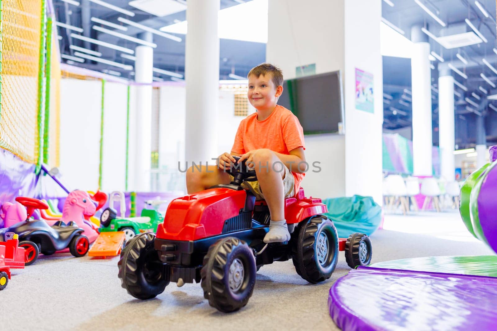 A child rides a toy pedal car at a children's play center.