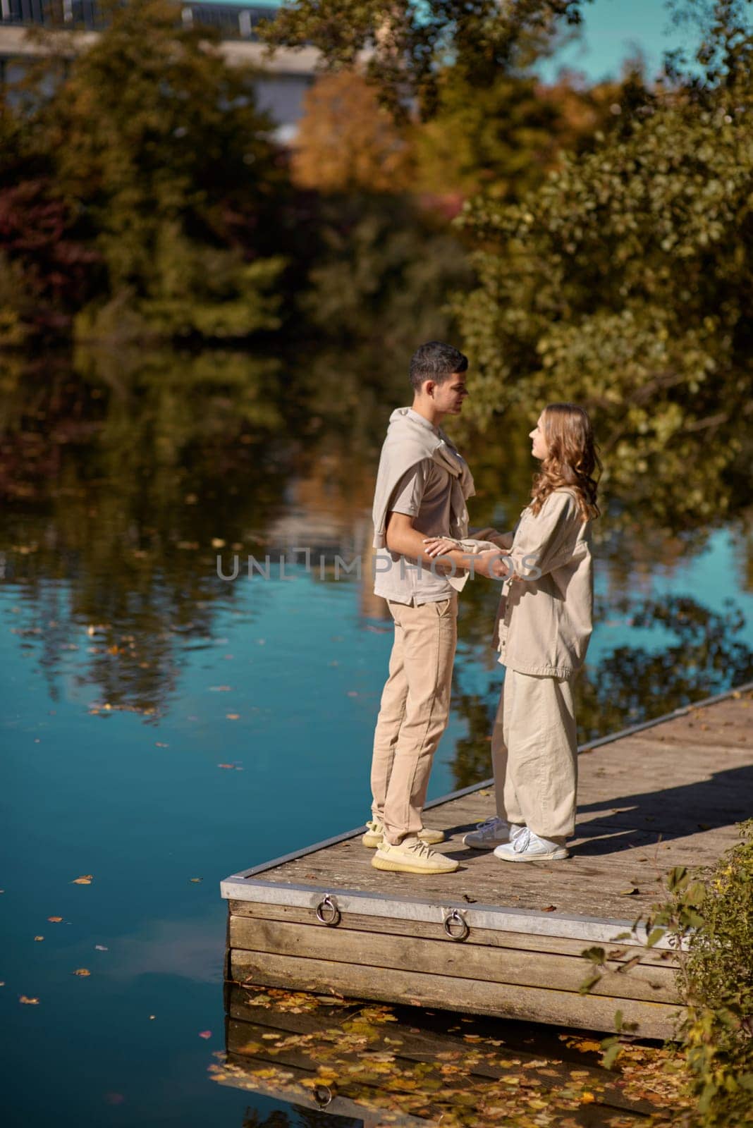 A happy couple in love in casual clothes travel together, hike and have fun in the fall forest on a weekend in nature in autumn outdoors, selective focus. Handsome man embracing with passion his girlfriend outdoor under the leaves of trees on the embankment. Love history. Happy people concept