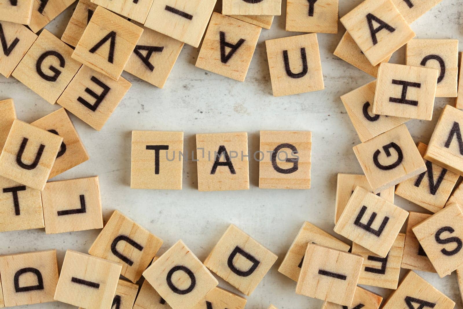 Top down view, pile of square wooden blocks with word TAG on white board. 