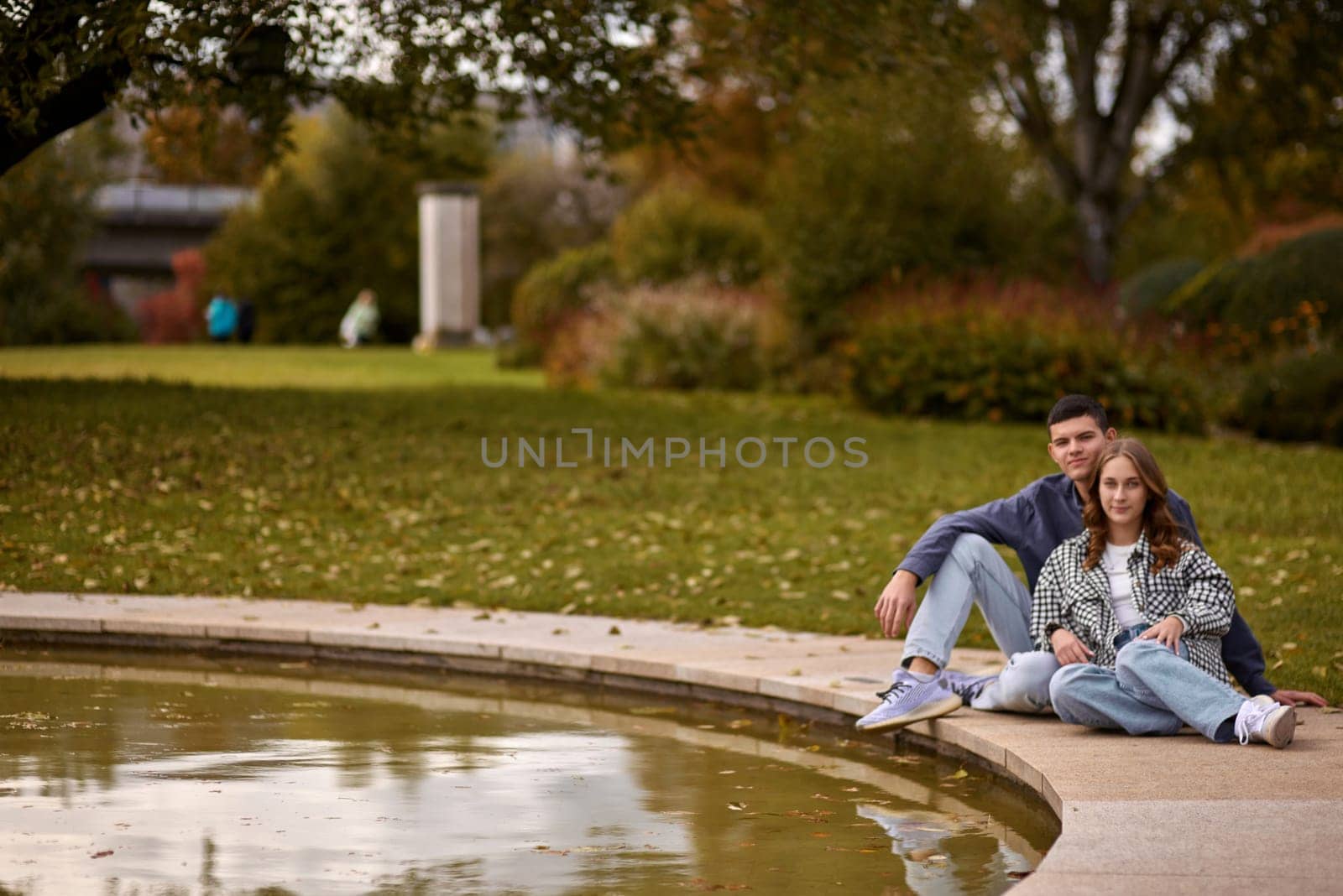 Young couple kissing and rejoices at the lake. lovely young couple kissing outdoors in autumn. Loving couple walking in nature. Autumn mood. Happy man and woman hugging and kissing in autumn. Love. Fashionable couple outdoors. Fashion, people and lifestyle. Stylish couple in autumn outfit. by Andrii_Ko