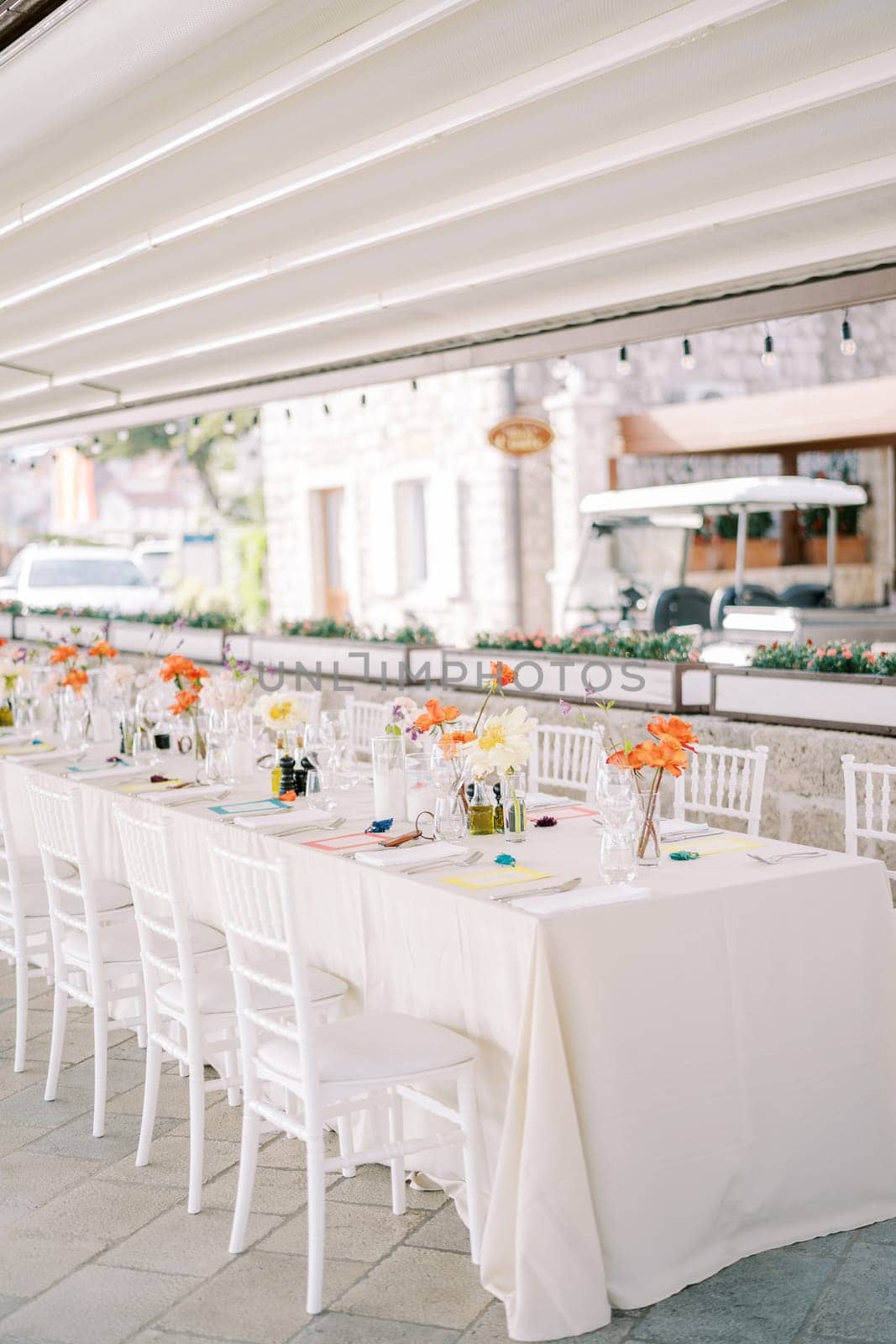 Bouquets of flowers stand on a festive long table under a canopy near the house. High quality photo