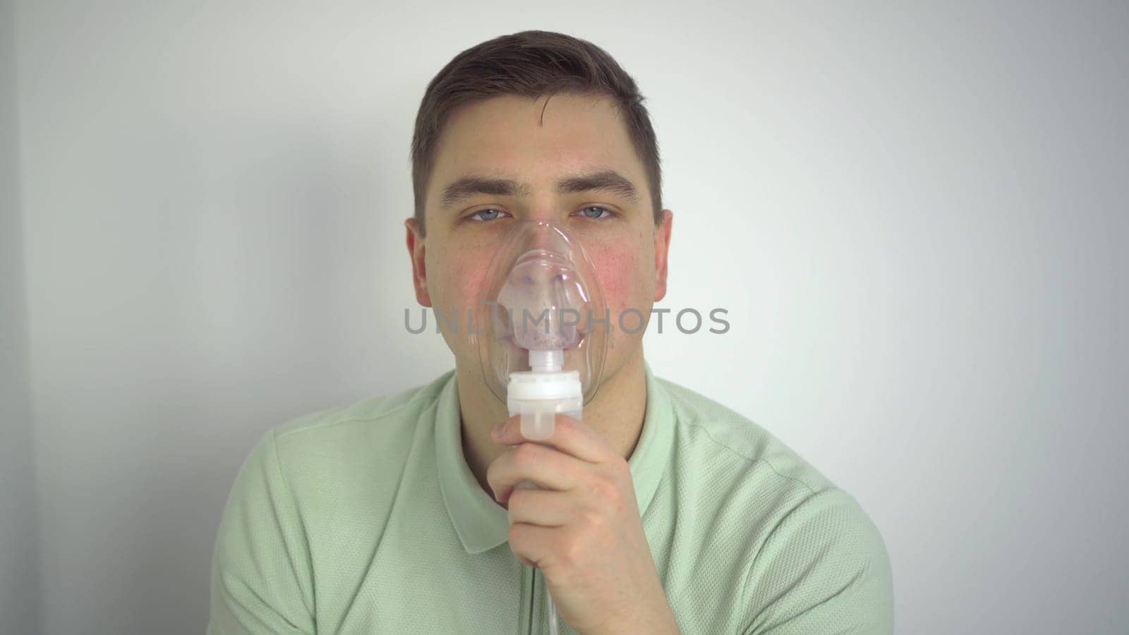 A young man breathes through an inhaler closeup. A man with an oxygen mask is being treated for a respiratory infection. 4k
