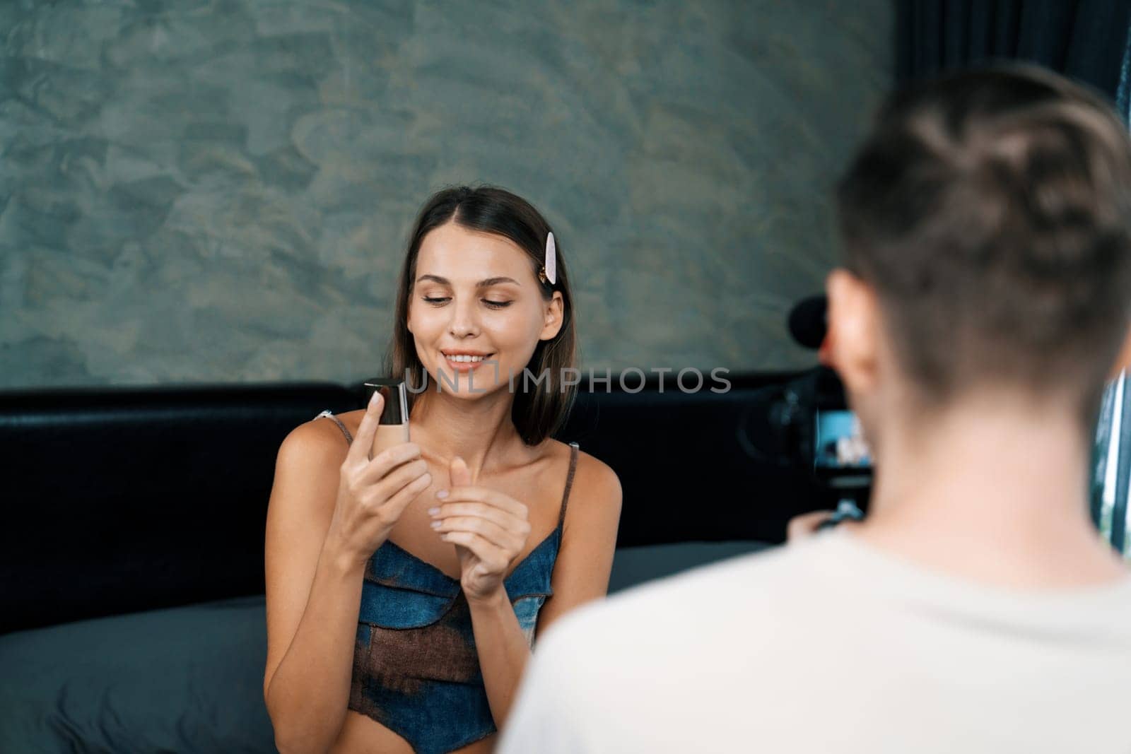 Man filming video on young woman making beauty and cosmetic tutorial video content for social media. Beauty blogger smiles to camera while showing how to beauty care to audience or follower. Unveiling