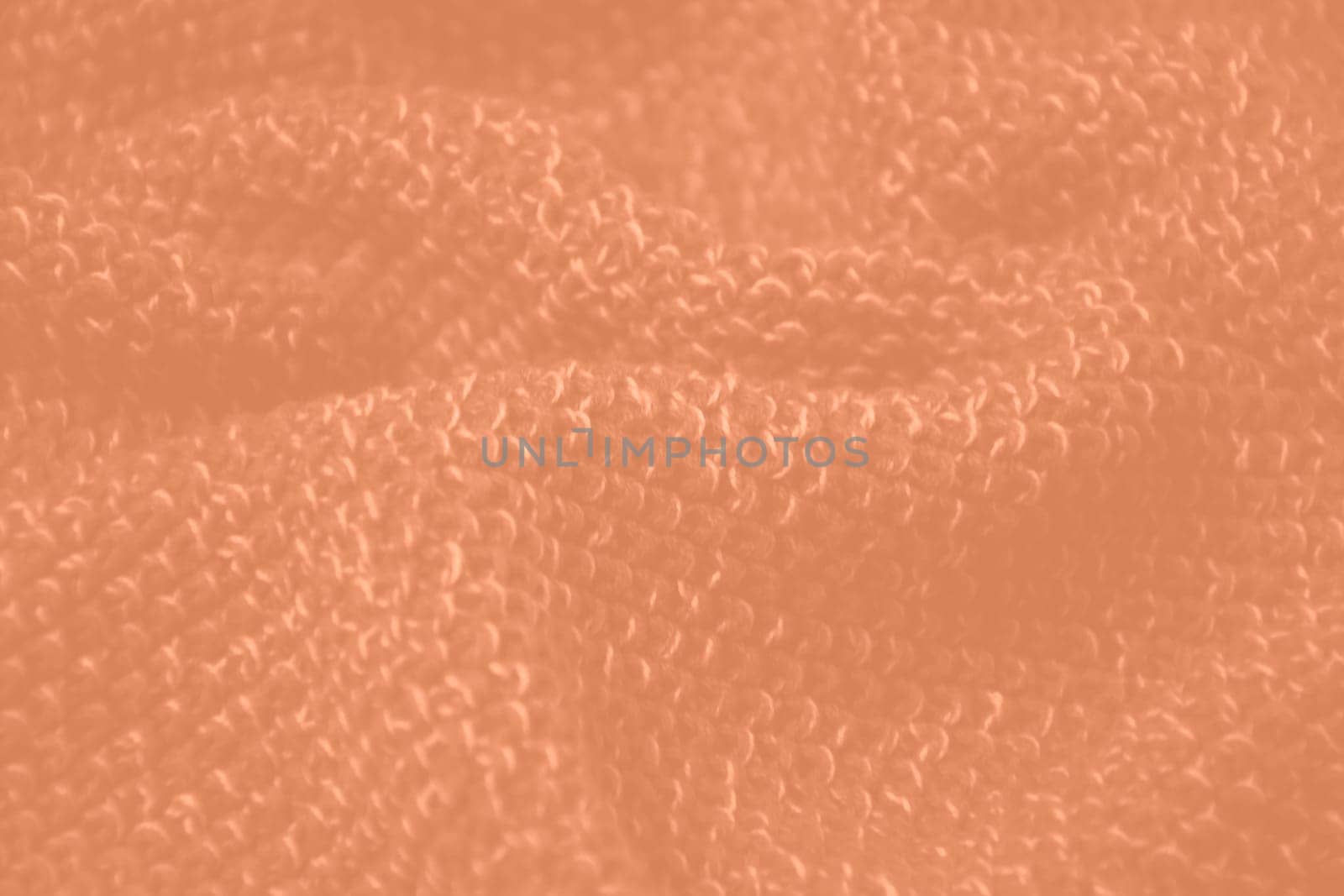 Peach fuzz colour monochrome texture knitted fabric. Peach knitted Jersey as textile background. Monochrome color background. Wool knitting texture. Trendy color 2024. High quality photo