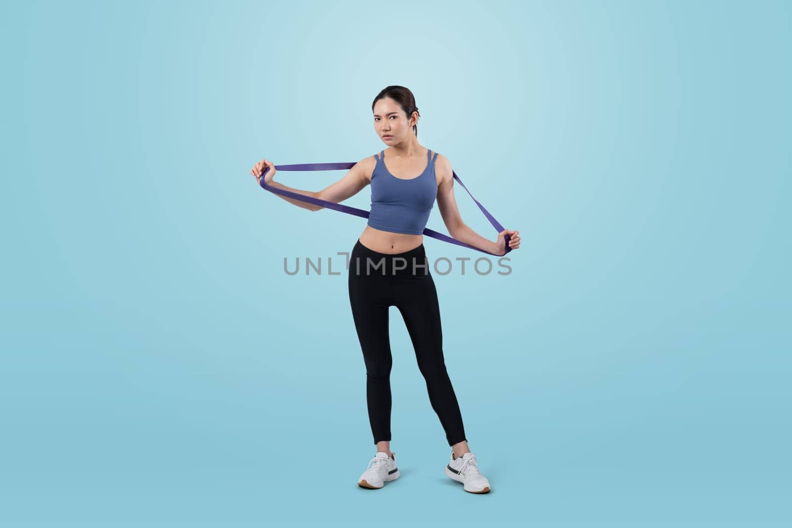 Vigorous energetic woman in sportswear portrait stretching resistance band. by biancoblue