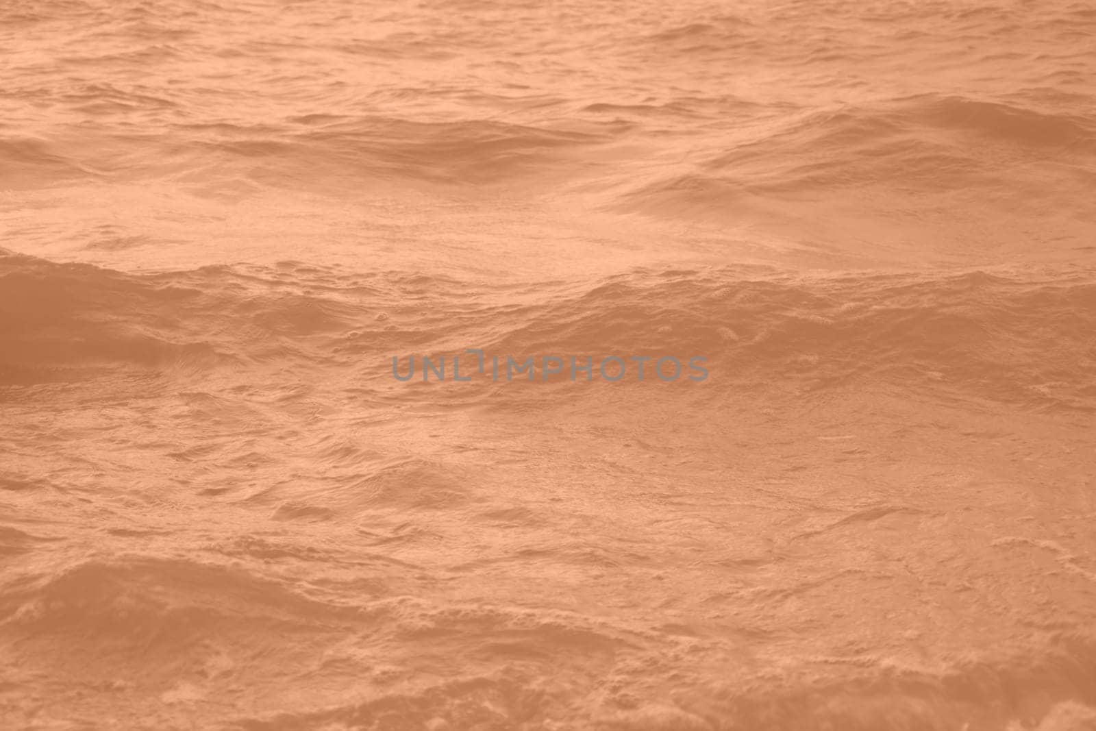 Peach Fuzz toned sea water texture. Pool water with sun reflections. Trendy colour 2024 year. High quality photo