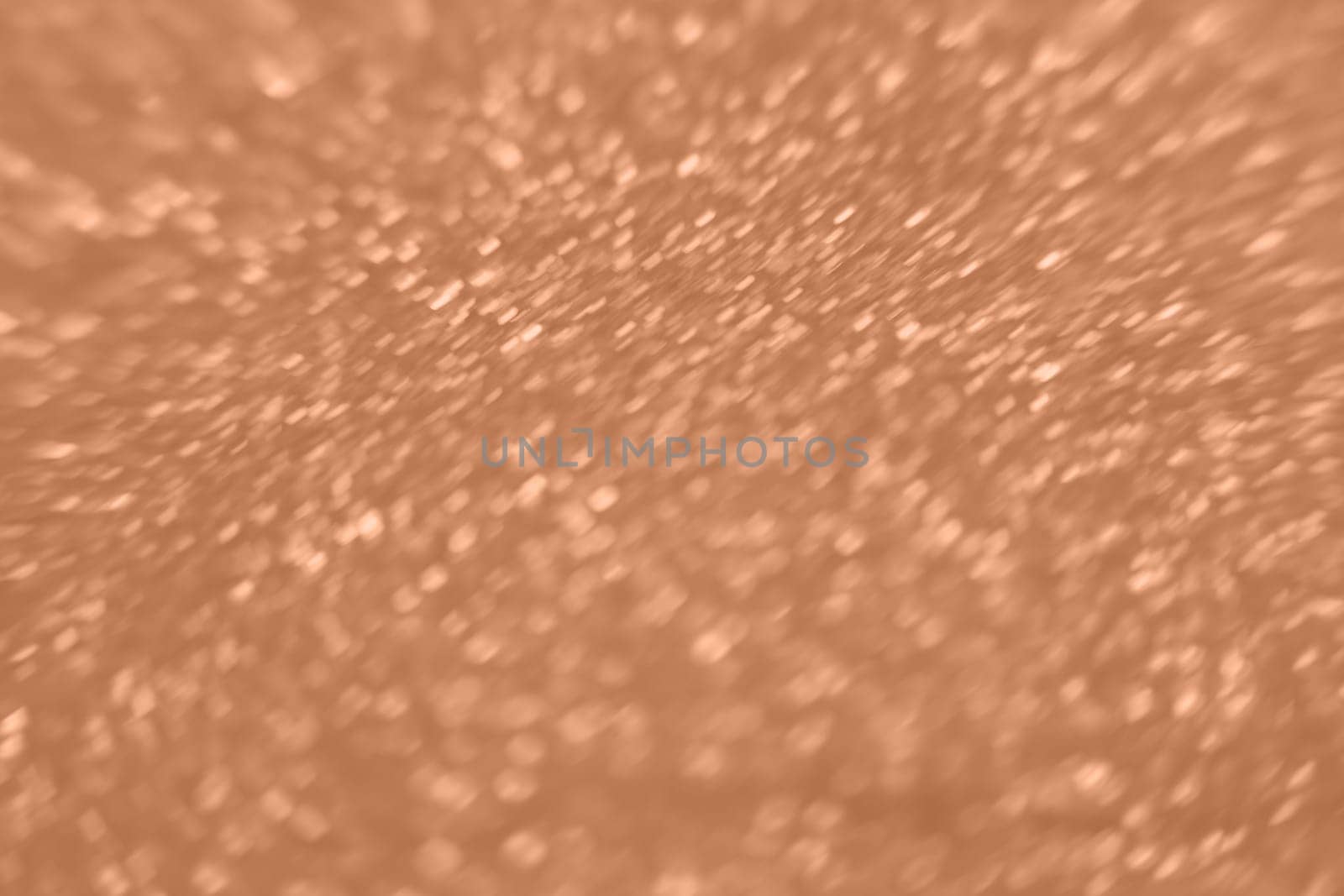 Peach Fuzz color glitter background. Blurred monochrome background with bokeh. Blurred glitters shimmering dust macro close up. High quality photo