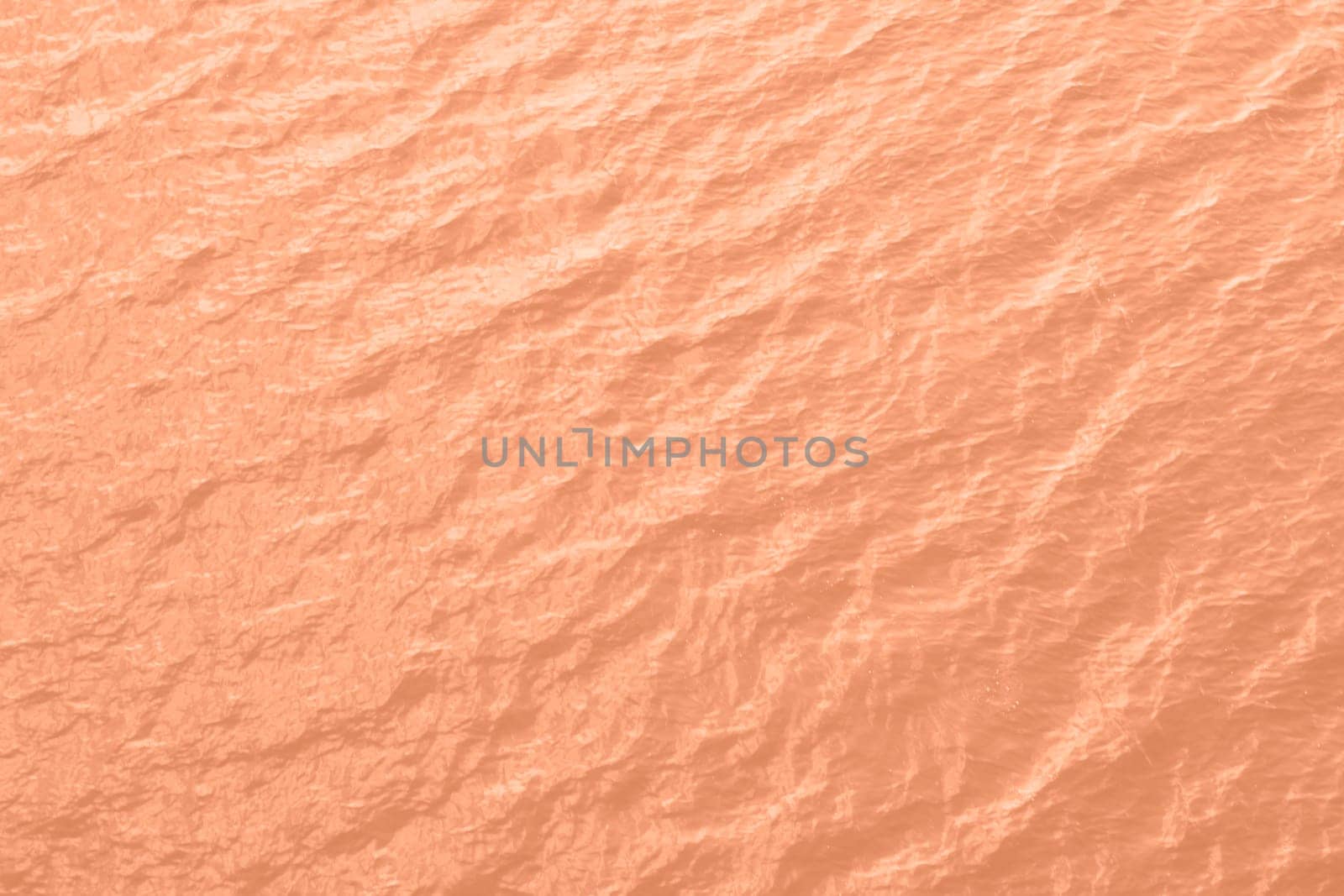 Peach Fuzz toned sea water texture. Pool water with sun reflections. Trendy colour 2024 year. High quality photo