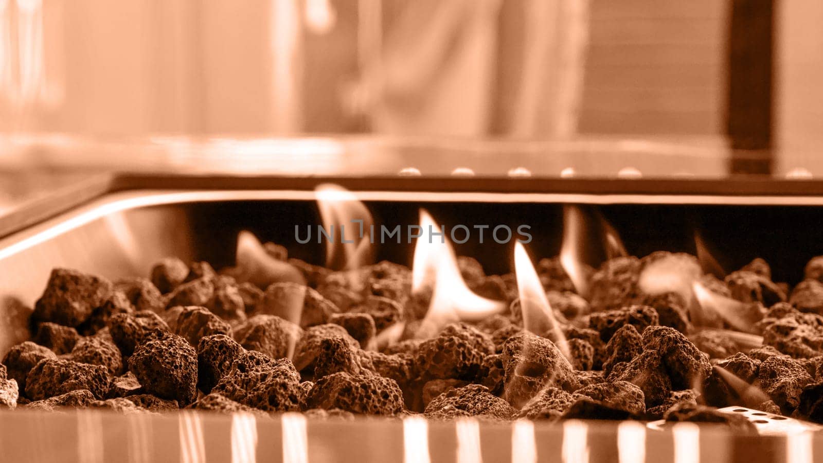 Stone firepit with fire flames. Image toned in Peach Fuzz color of the year 2024. Summer camping bonfire