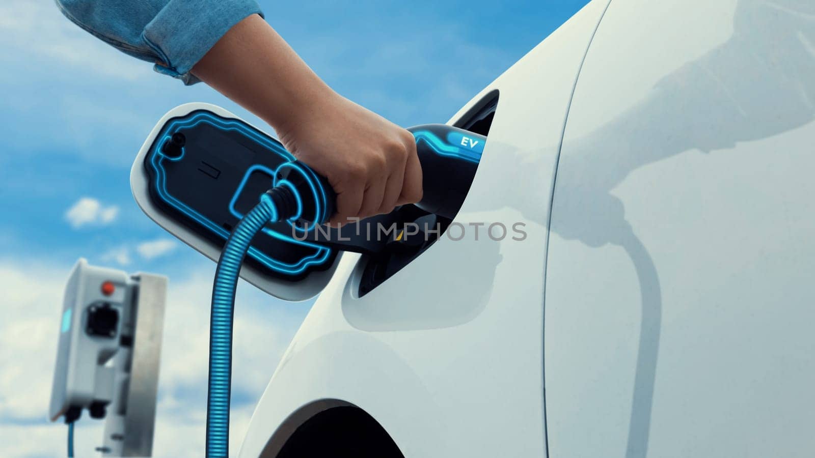Asian man recharging his electric car with EV charger. Peruse by biancoblue